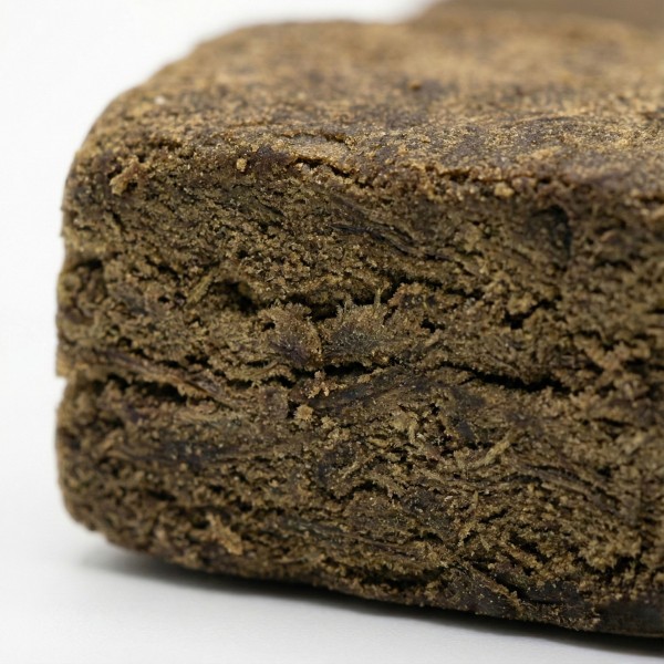 Gros plan sur la texture sombre et compacte du BBM Hash CBD bio. Résine de chanvre artisanale