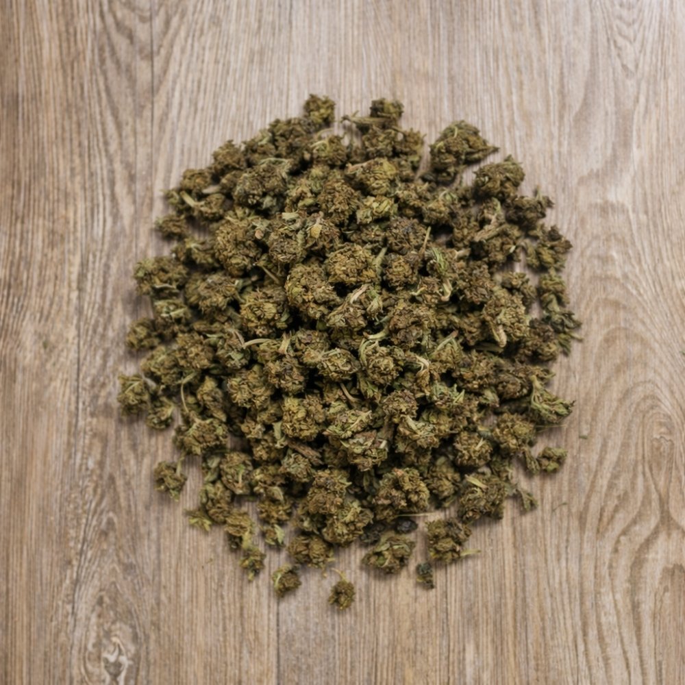 Tas de petites fleurs CBD Cannatonic en vrac pose sur surface en bois.