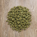 Tas de petites fleurs CBD Surver Haze en vrac pose sur surface en bois.