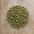Tas de petites fleurs CBD Surver Haze en vrac pose sur surface en bois.