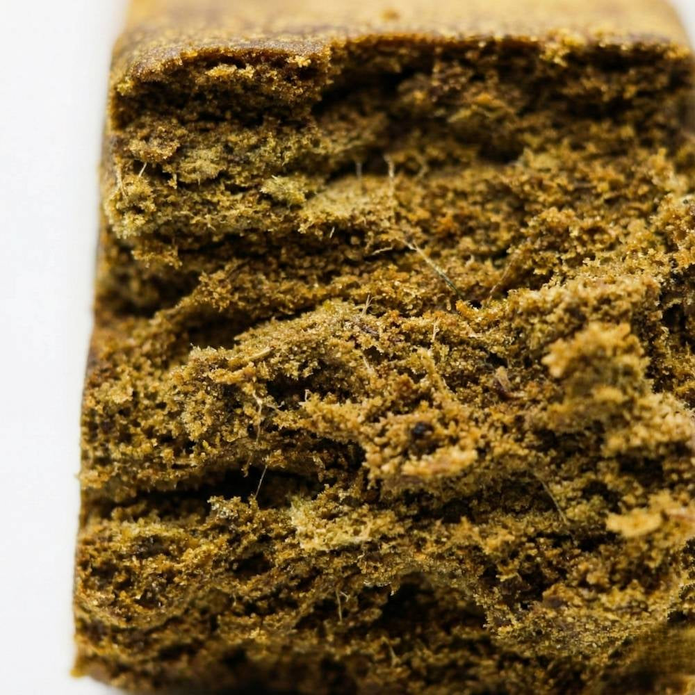 Macro bloc de hash CBD montrant texture compacte et surface granuleuse.