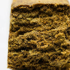 Macro bloc de hash CBD montrant texture compacte et surface granuleuse.