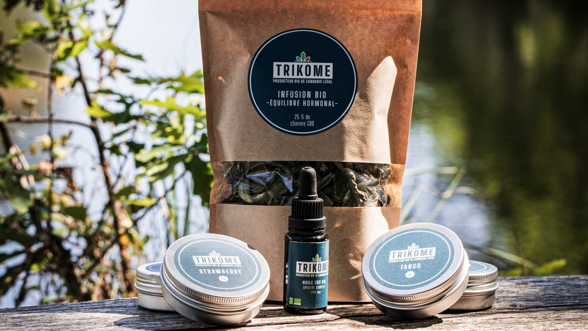 Gamme de produits CBD bio Trikome présentée en extérieur : infusion bio au chanvre CBD, huile CBD bio spectre complet et fleurs de CBD