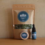 Sachet infusion bio, baume CBD 20 ml et huile CBD Trikome poses sur table.