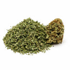 Trim CBD bio Hawaiian Haze avec fragments végétaux et une bud riche en terpènes sur fond blanc.
