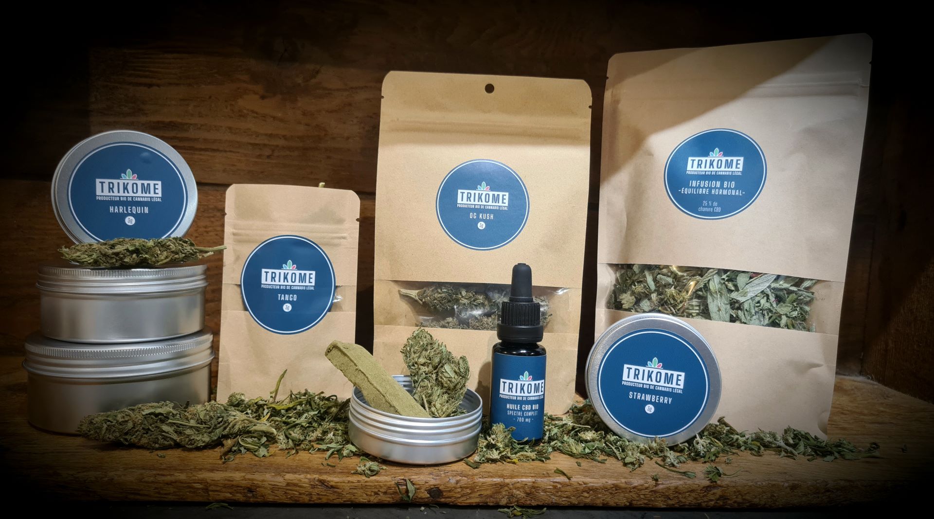 Gamme de produits CBD Trikome issus d'une production locale en Savoie, comprenant des fleurs de chanvre séchées, de l’huile de CBD en flacon compte-gouttes et un pré-roll, présentés dans un packaging artisanal et naturel.